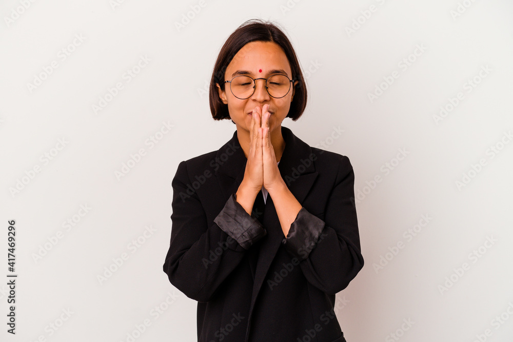 Young business Indian woman isolated on white background holding hands in pray near mouth, feels confident. Young business Indian woman isolated on white background holding hands in pray near mouth, feels confident.