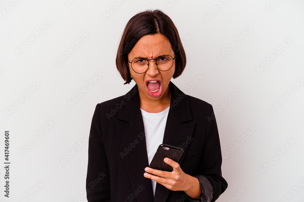 Young indian business woman holding a phone isolated Young business indian woman holding a phone isolated screaming very angry and aggressive. Young indian business woman holding a phone isolated Young business indian woman holding a phone isolated screaming very angry and aggressive.