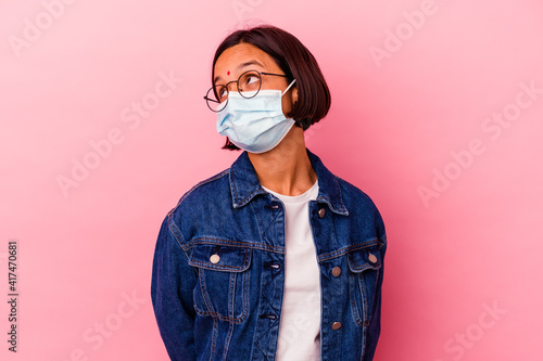 Young Indian woman wearing a mask antivirus isolated on pink background dreaming of achieving goals and purposes © Asier
