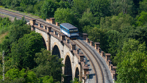 A train passing over an old stone bridge in Prague. The bridge is called Prague Semering photo