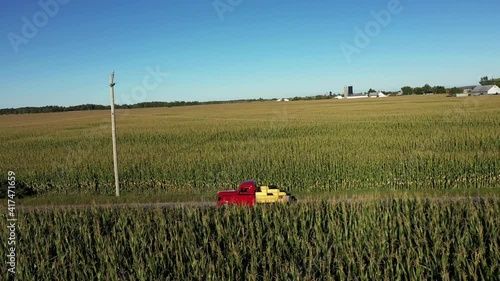 vintage red truck driving through cornfields aerial side follow