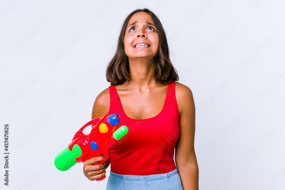 Young mixed race woman holding a water gun isolated shouting very angry, rage concept, frustrated. Young mixed race woman holding a water gun isolated shouting very angry, rage concept, frustrated.