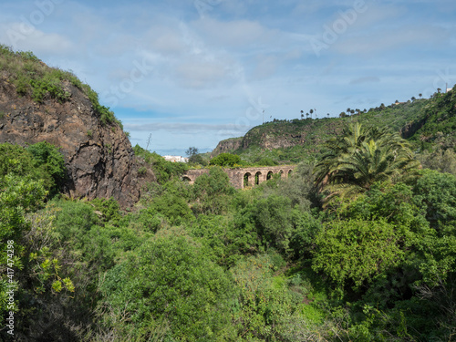 Green valley with old stone viaduct or aqueduct view from terrace at botanical garden, Jardin Botanico Canario Viera y Clavijo, Tafira, Gran Canaria, Canary Islands, Spain
