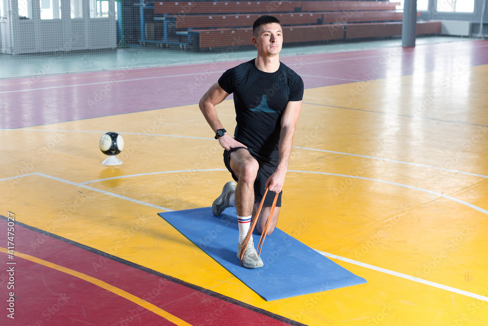 Athletic guy in sportswear and fitness tracker doing exercises in gym.