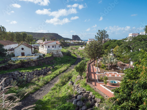 View from Agaete city towards Puerto de las Nieves with Roque de las Nieves rock, park, trees and dried river canal photo