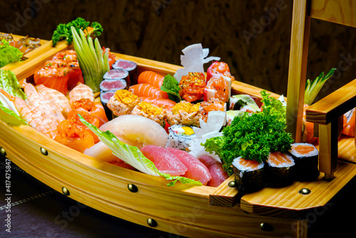 Sushi sashimi set in a wooden boat on a brown photo