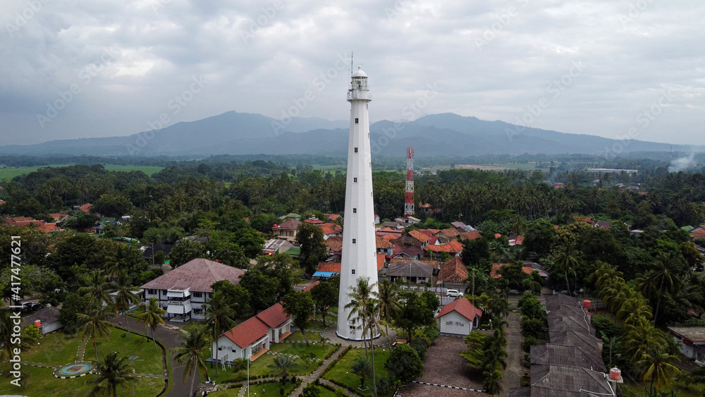 Aerial view of Lighthouse sea rock sunset landscape. Sunset lighthouse scene. At anyer beach with noise cloud and cityscape.