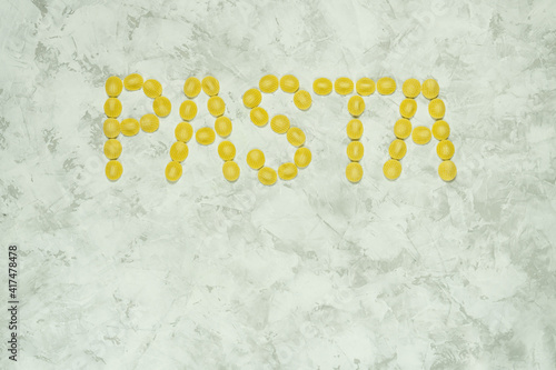 Inscription of word Pasta made from raw orecchiette type of pasta on grey background with space for text. photo