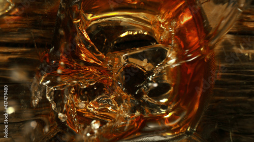 Top shot of ice cube splashing into glass of whisky