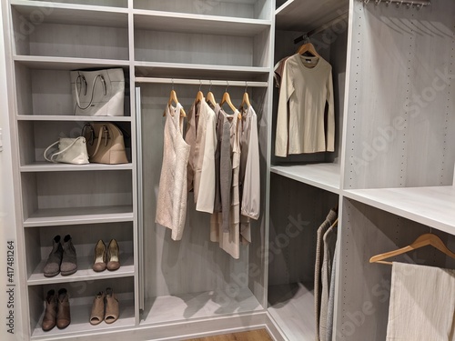walk in closet with shirts and pants hanging up on hangers and shoes on the shelving