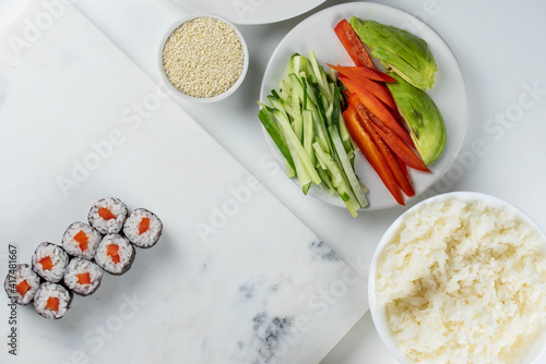 Sushi rolls prepared by professional asian chef with traditional Japanese ingredients. Salmon, rice, vegetables, sesame seeds. Sushi cooking and making concept