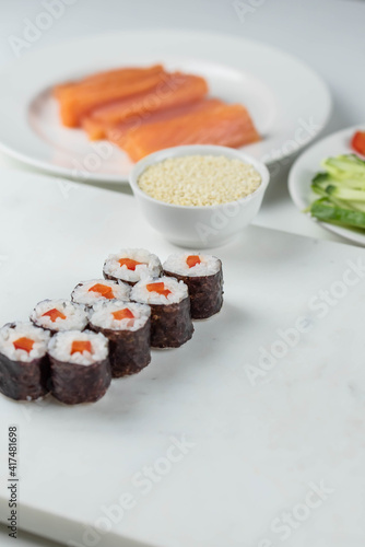 Sushi rolls prepared by professional asian chef with traditional Japanese ingredients. Salmon, rice, vegetables, sesame seeds. Sushi cooking and making concept