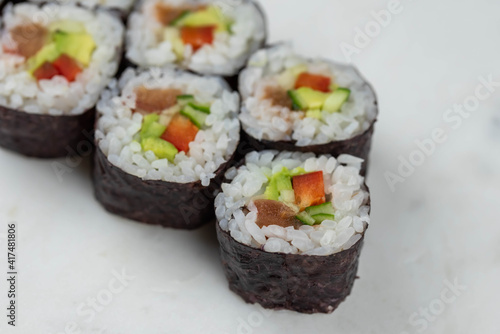 Sushi rolls prepared by professional asian chef with traditional Japanese ingredients. Salmon, rice, vegetables, sesame seeds. 