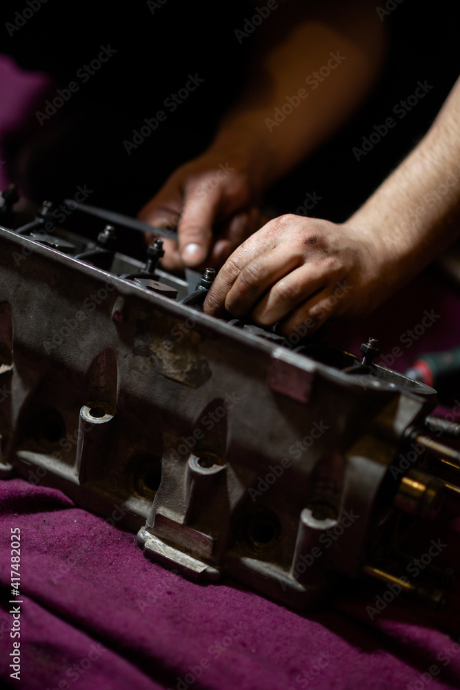 blurred image, male hands adjusting valve clearances on the cylinder head. cylinder head repair blurred image, male hands adjusting valve clearances on the cylinder head. cylinder head repair