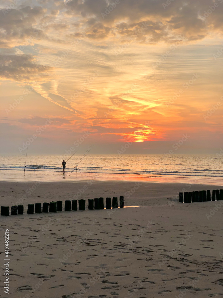 Fototapeta premium Angler bei Sonnenuntergang an der Niederländischen Nordsee