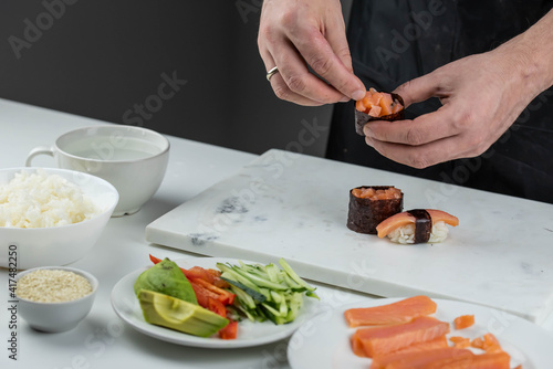 Closeup of chef hands preparing japanese food. Professional chef making sushi at restaurant. Man hands making traditional asian sushi rolls on cutting board.