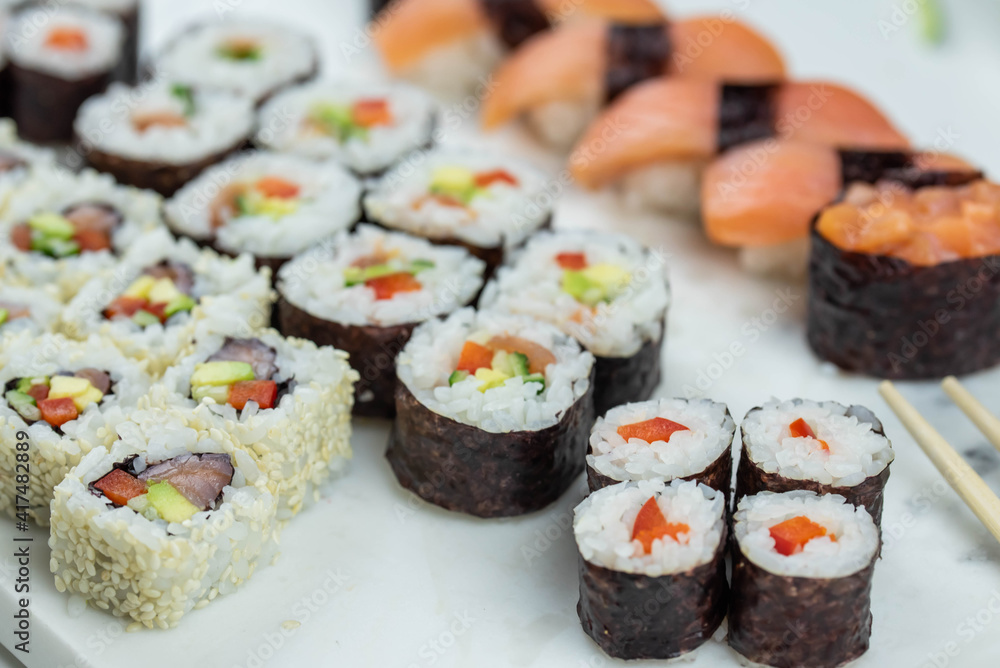 Sushi rolls prepared by professional asian chef with traditional Japanese ingredients. Salmon, rice, vegetables, sesame seeds. Sushi rolls prepared by professional asian chef with traditional Japanese ingredients. Salmon, rice, vegetables, sesame seeds.