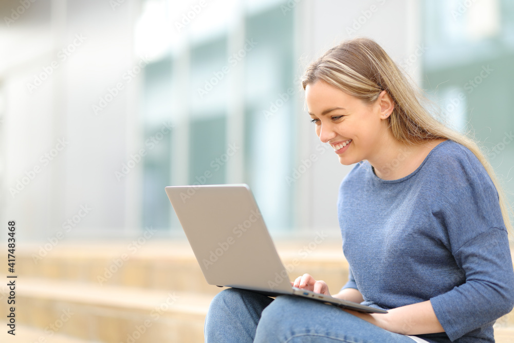 Fototapeta premium Happy teen checking laptop in the street