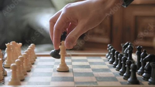A man moves chess pieces on a chessboard. Against the background of vintage old things. Game of Chess.Player makes a move, developing chess strategy, play board game with opponent.