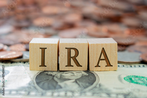 Wooden block with the letter IRA with some money around. Concept: Retirement Plan in USA, Individual Retirement Account