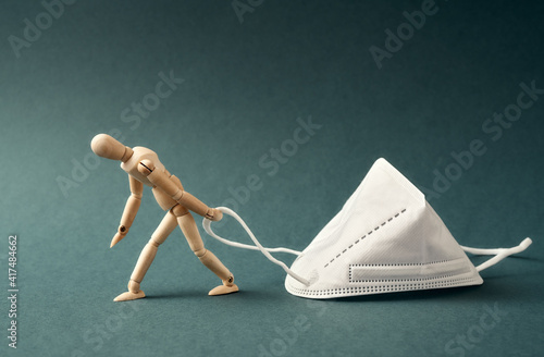 Tired figure dragging a white FFP2 or KN95 respirator, destined to prevent the coronavirus or COVID-19 pandemic