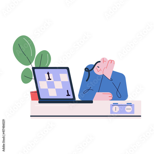 Young pensive man sitting and playing chess online on laptop