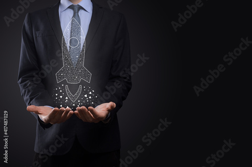 Startup business concept, Businessman holding icon transparent rocket is launching and soar flying out from screen with network connection on dark background.