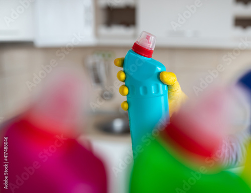 Woman taking bottle with cleaning detergent from shelf in pantry