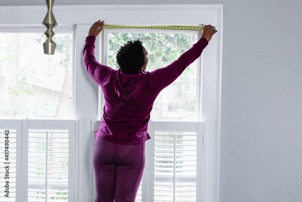 DIY, woman uses tape measure tool on window DIY, woman uses tape measure tool on window