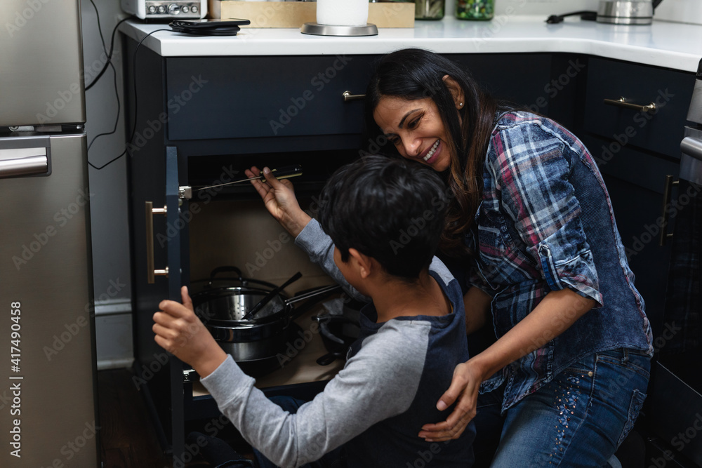 © Gerald Carter/Creative Flame - Indian mother teaches son how to repair kitchen cabinets, DIY home improvement
