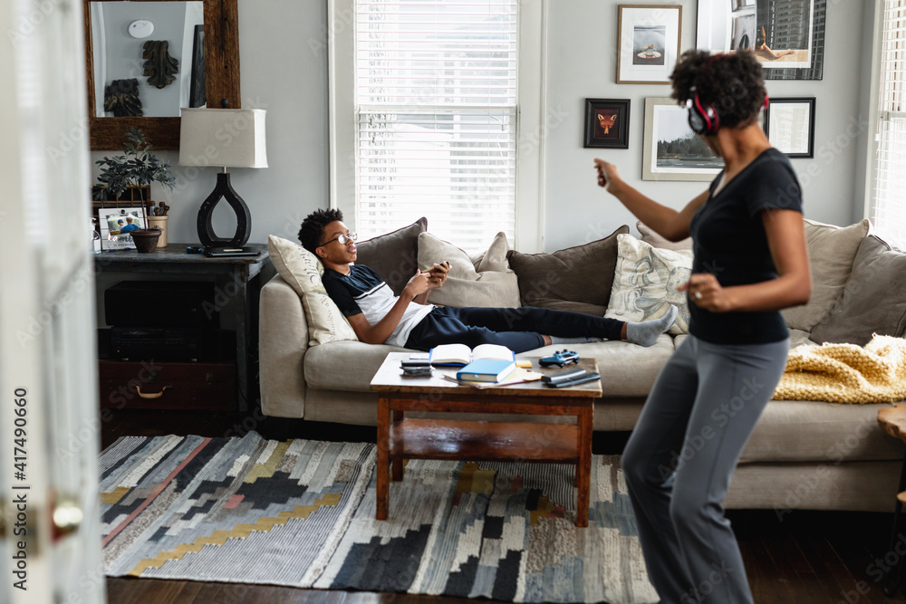 Black mom enjoys music, dancing in family room, son in background, weekend morning Black mom enjoys music, dancing in family room, son in background, weekend morning