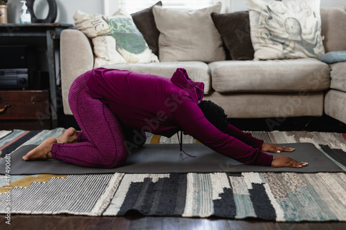 Black woman doing childs pose at home in living room, yoga flow