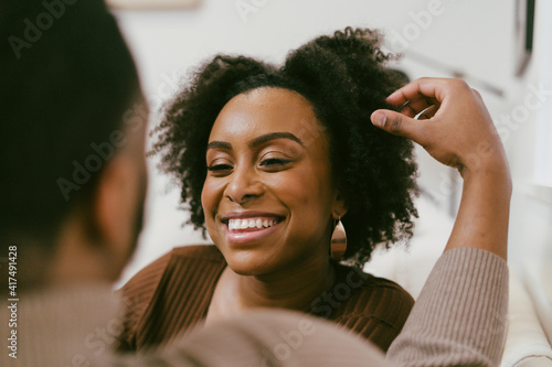 Intimate coversation, black couple at home, man plays with hair, affectionately photo