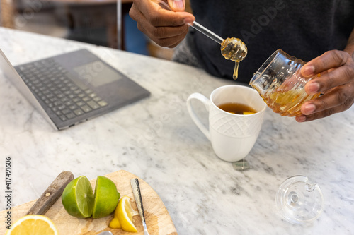Black man adds honey sweetener to tea drink