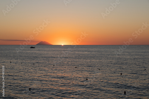 Amazing view of the Stromboli Volcano at sunset  wit the sun going down and amazing sea and sky colors. View form the coast of Calabria  Italy  in the touristic destination of Tropea.