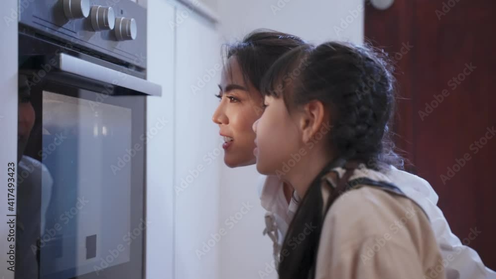 Asian young mother and daughter baking pizza by oven in the kitchen. Asian young mother and daughter baking pizza by oven in the kitchen.