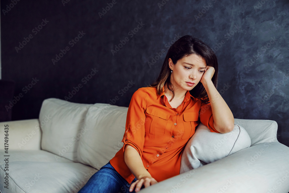 Unhappy woman sitting on the sofa and thinking. She is very depressed. Mental illness award day. Unhappy woman sitting on the sofa and thinking. She is very depressed. Mental illness award day.