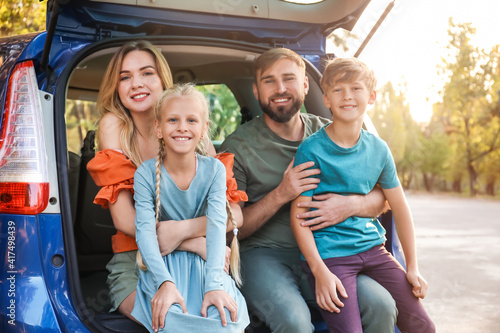 Happy family sitting in car trunk outdoors © Pixel-Shot