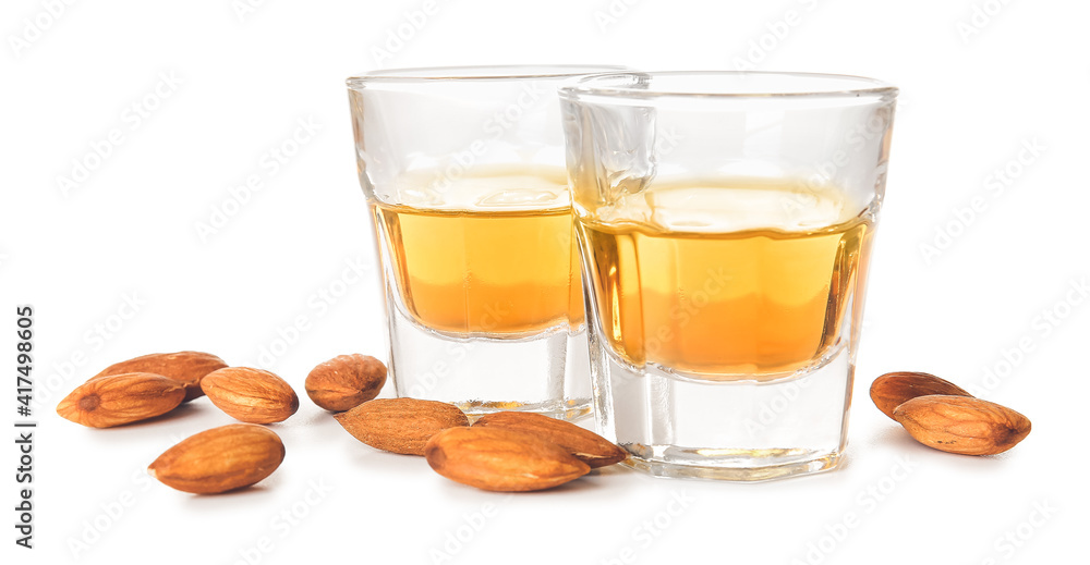 Glasses of almond liquor and nuts on white background Glasses of almond liquor and nuts on white background