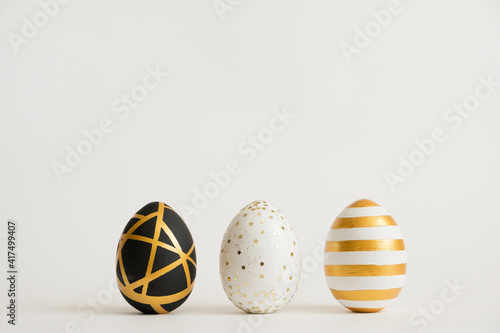 Photography Three Easter golden decorated eggs isolated on white background