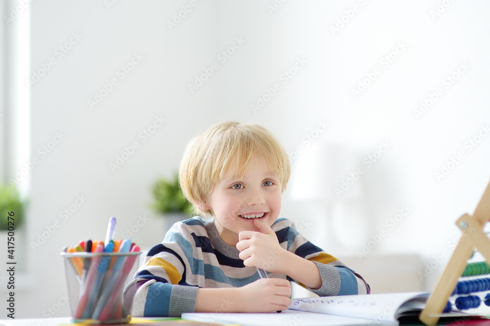 Elementary student boy doing homework at home. Child learning to count, solves arithmetic examples, doing exercises in workbook. Math tutorial. Preparing preschooler baby for school. Education Elementary student boy doing homework at home. Child learning to count, solves arithmetic examples, doing exercises in workbook. Math tutorial. Preparing preschooler baby for school. Education
