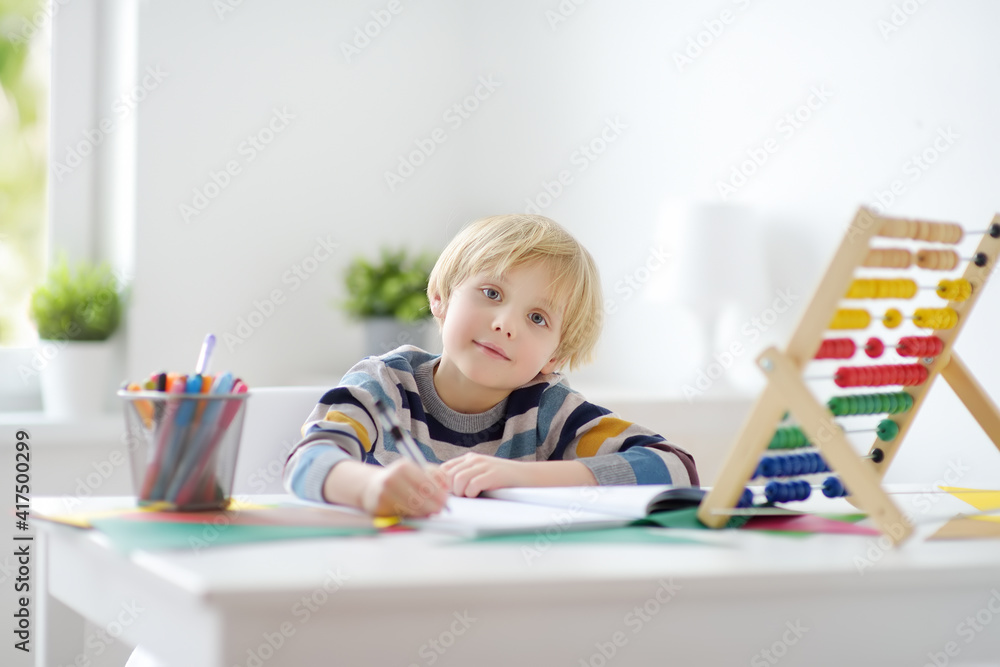 Elementary student boy doing homework at home. Child learning to count, solves arithmetic examples, doing exercises in workbook. Math tutorial. Preparing preschooler baby for school. Education Elementary student boy doing homework at home. Child learning to count, solves arithmetic examples, doing exercises in workbook. Math tutorial. Preparing preschooler baby for school. Education