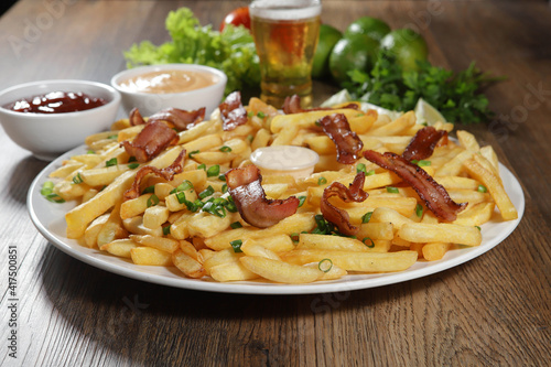 Portion of french fries with bacon. Lettuce, potato, green onion, tomato, ketchup and mayonnaise