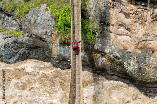 Quechua woman crossing Queshuachaca (Q'eswachaka) rope bridge, one of the last standing Incan handwoven bridges, Quehue, Canas Province, Peru photo