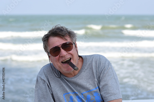 A senior Caucasian man smoking cigar at the beach. Hua Hin beach, Thailand.