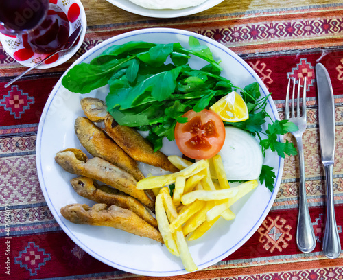 Crispy pan-fried red mullet served with fries, fresh tomato slice, greens and lemon. Turkish cuisine. photo