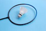Shuttlecock and badminton racket on blue background.
