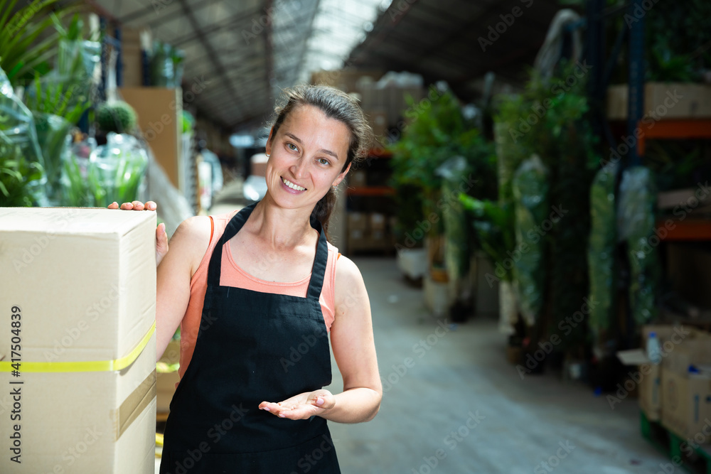 Portrait of friendly female garden store worker posing at shopping room