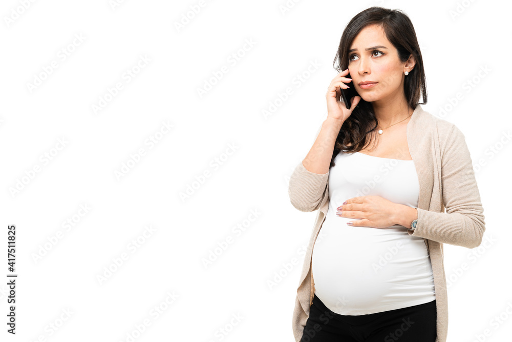 Pregnant woman looking scared while talking on the phone Pregnant woman looking scared while talking on the phone