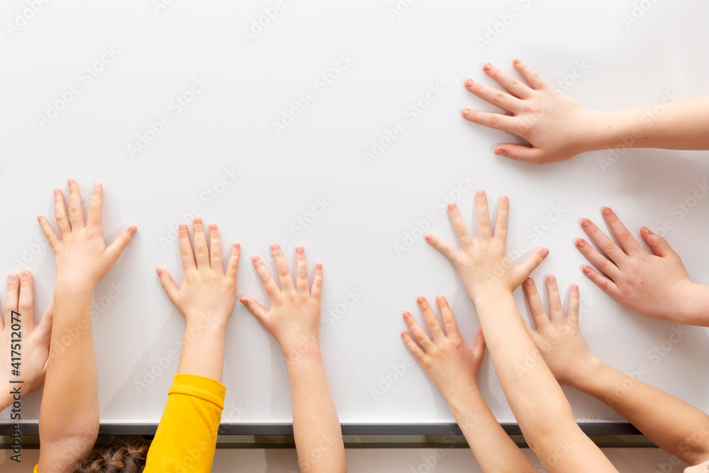 many children's hands on the background of a white school board. empty space for inscription many children's hands on the background of a white school board. empty space for inscription